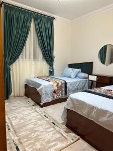 a bedroom with two beds with green curtains at Two million hotel 2 in 6th Of October