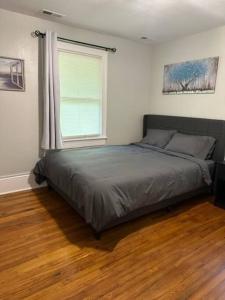 Schlafzimmer mit einem Bett, einem Fenster und Holzböden in der Unterkunft 6 BR Home near Football Stadium! in Greenville