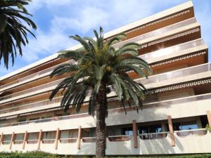 a palm tree in front of a building at Bel appartement avec terrasse, piscine, parking et WiFi - FR-1-196-321 in Menton