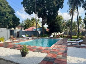una piscina en un patio con bancos y árboles en BBQ Lounge, en Dar es Salaam