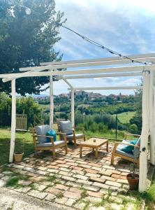 a pergola with chairs and a table on a patio at L'Antica Colombaia; Apartment with private entrance in Ostra