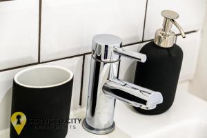 a bathroom sink with a soap dispenser and a faucet at SCA- Arden Apartment 4 Twin Bedroom Free Parking in Coventry