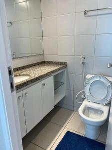 a bathroom with a toilet with its seat up and a sink at Terraços do Atlântico - Apto Beira Mar Fortaleza in Fortaleza