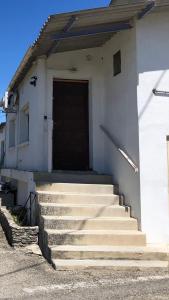 a white building with stairs leading to a door at Studio Proche L'Isle sur Sorgue in Le Thor