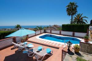 a swimming pool with chairs and a blue umbrella at Villa Yolanda del Mar in Arroyo de la Miel