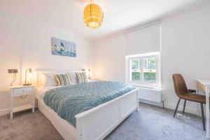 a bedroom with a bed and a desk and a window at The Lymington Sailor's Cottage in Lymington