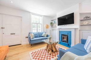 a living room with a blue couch and a fireplace at The Lymington Sailor's Cottage in Lymington