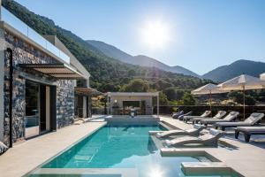 uma villa com uma piscina com montanhas ao fundo em Troia Villas em Balíon