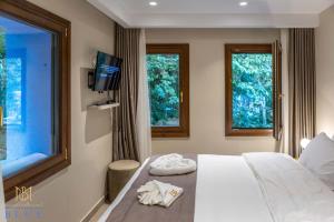 a bedroom with a bed with a tv and two windows at Moustheni Blue Guest House in Mousthéni