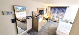 a hotel room with a bedroom with a bed and a mirror at La Quinta by Wyndham Lexington Park - Patuxent in California