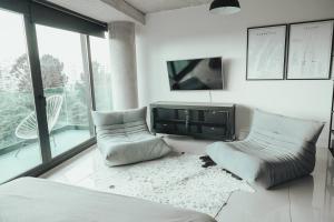 a bedroom with two chairs and a bed and a tv at Mansion Botánico Premium Buenos Aires in Buenos Aires