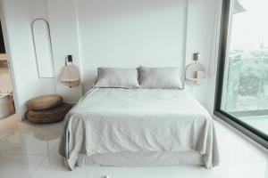 a white bed in a white bedroom with a window at Mansion Botánico Premium Buenos Aires in Buenos Aires
