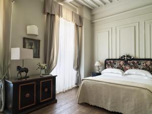 a bedroom with a bed and a large window at Villa di Piazzano - Small Luxury Hotels of the World in Cortona