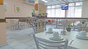 comedor con mesas y sillas y TV en Hotel St. John, en Blumenau