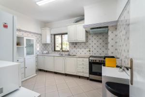 La cuisine est équipée de placards blancs et d'un four avec plaques de cuisson. dans l'établissement Lively Charming Apartment w Pool, à Praia do Carvoeiro