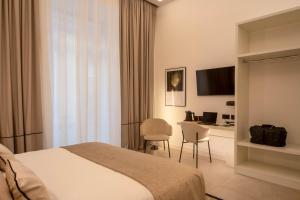 una camera d'albergo con letto, tavolo e sedie di MAMALU - Studios and Suites a Napoli