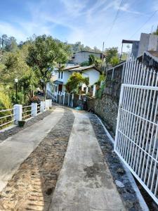 a white fence next to a street with a house at Elegant Hotel in Bandarawela