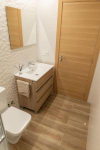 een badkamer met een wastafel, een toilet en een spiegel bij Casa Tía Pepa 