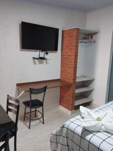 Habitación con escritorio y TV en la pared. en Rifugio en Alto Paraíso de Goiás