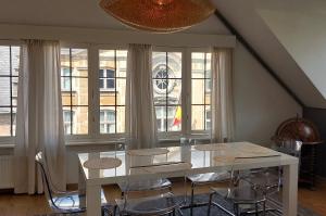 een witte tafel en stoelen in een kamer met ramen bij The Roof - Rooftop appt in historical center in Antwerpen