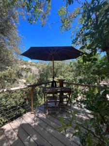 une table et une chaise avec un parasol sur une terrasse dans l'établissement Chalet dans les arbres, à Nice