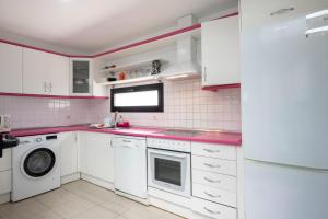 una cocina con armarios blancos y encimeras rosas en Pink Waves House en El Médano