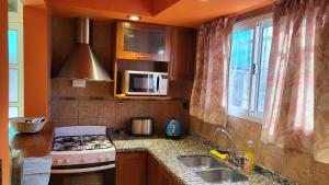 a kitchen with a stove and a sink and a microwave at Casa de vacaciones, alquiler temporario en La Falda in La Falda +24 photos