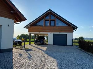 uma casa com uma garagem com um carro estacionado nela em Apartamenty Eksploris em Kudowa-Zdrój