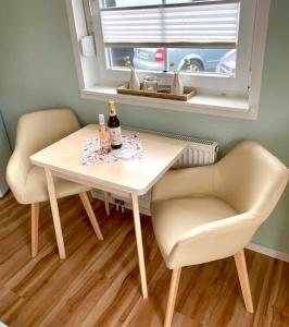 a table with two chairs and a bottle of wine at Ferienzimmer/wohnung am Kurstrand, WLAN in Zingst