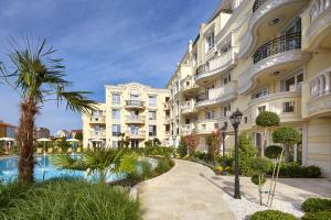 an apartment building with a swimming pool and palm trees at Bellicity Apart Complex in Ravda