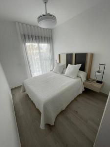 Un dormitorio blanco con una cama blanca y una ventana en Elisa Apartment, en San Javier