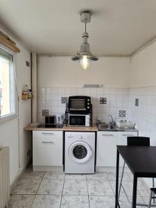 une cuisine avec un lave-linge et un micro-ondes dans l'établissement Couturier lovely appartement proche centre ville, à Reims