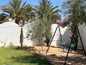 einen Garten mit einer Schaukel und einem Reifen in der Unterkunft VillaLina Haut Standing Djerba in Ajim