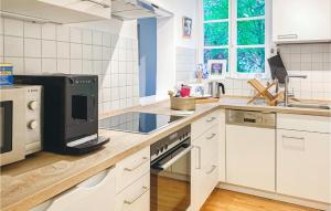 une cuisine avec des armoires blanches et un appareil noir dans l'établissement 1 Bedroom Beautiful Apartment In Morschen, à Morschen