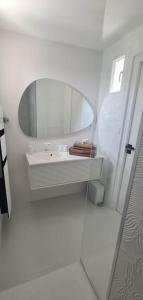 een witte badkamer met een spiegel en een wastafel bij Le rêve de Déborah in Cap d'Agde