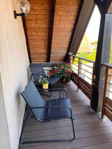 un porche con 2 sillas, una mesa y flores en Appartement Stotzheim La Romaine, en Stotzheim