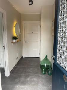 um corredor com uma porta branca e um vaso verde em Klein Nienoord Midwolde em Midwolde