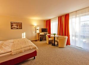 Habitación de hotel con cama, escritorio y mesa. en Hotel Zur Sonne en Waren
