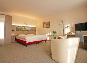 Dormitorio con cama, escritorio y TV en Hotel Zur Sonne en Waren
