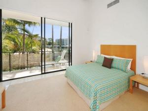 ヌーサヘッズにあるLuxury Retreat with Private Beach & Jettyのベッドルーム1室(ベッド1台付)、ヤシの木が茂るバルコニーが備わります。 +6枚の写真
