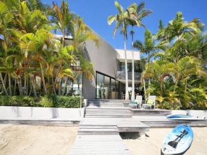 a building with palm trees and a surfboard on the beach at Cascade, 15 Witta Circle, Noosa Heads in Noosa Heads