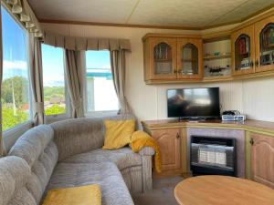 a living room with a couch and a tv at Holiday Home by the sea in Aberystwyth