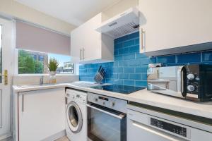 a kitchen with a washing machine and blue tiles at Bourne Court Attractive 1 bedroom Apt by MDPS in Ruislip