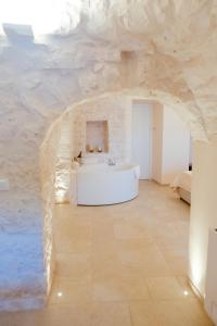 La salle de bains est pourvue d'une baignoire blanche et d'un mur en pierre. dans l'établissement Iconica Luxury Suites, à Alberobello