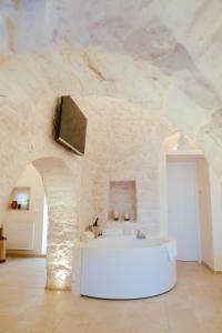 La salle de bains est pourvue d'un lavabo blanc et d'un mur en pierre. dans l'établissement Iconica Luxury Suites, à Alberobello
