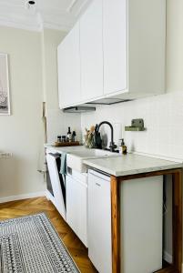 a kitchen with white cabinets and a sink at Ultracentral Lux Boutique 1BR Ap Near Subway in Bucharest +16 photos