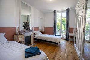 um quarto de hotel com duas camas e um espelho em La Demeure du Tabellion em Le Mont-Dore