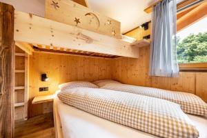 two beds in a room with wooden walls at Forchnerhof Apt 3 in Terento