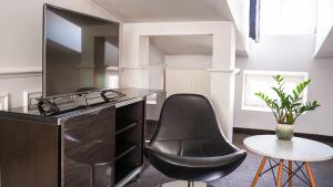 a black chair sitting next to a desk with a television at Hotel Grodzka 20 in Lublin