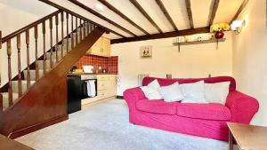 a living room with a red couch and a staircase at Curry Mallet Cottages in Taunton
